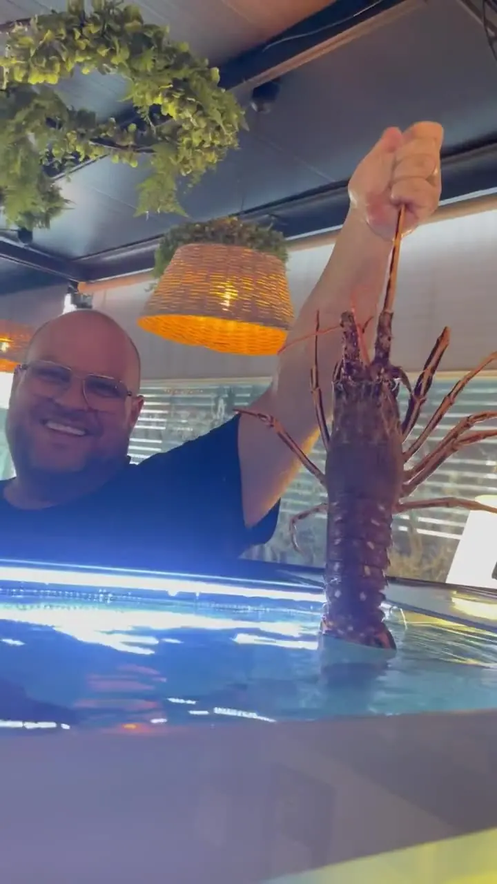 Diogo tient une langouste vivante (langosta) au-dessus du vivier de son restaurant de fruits de mer à Marbella