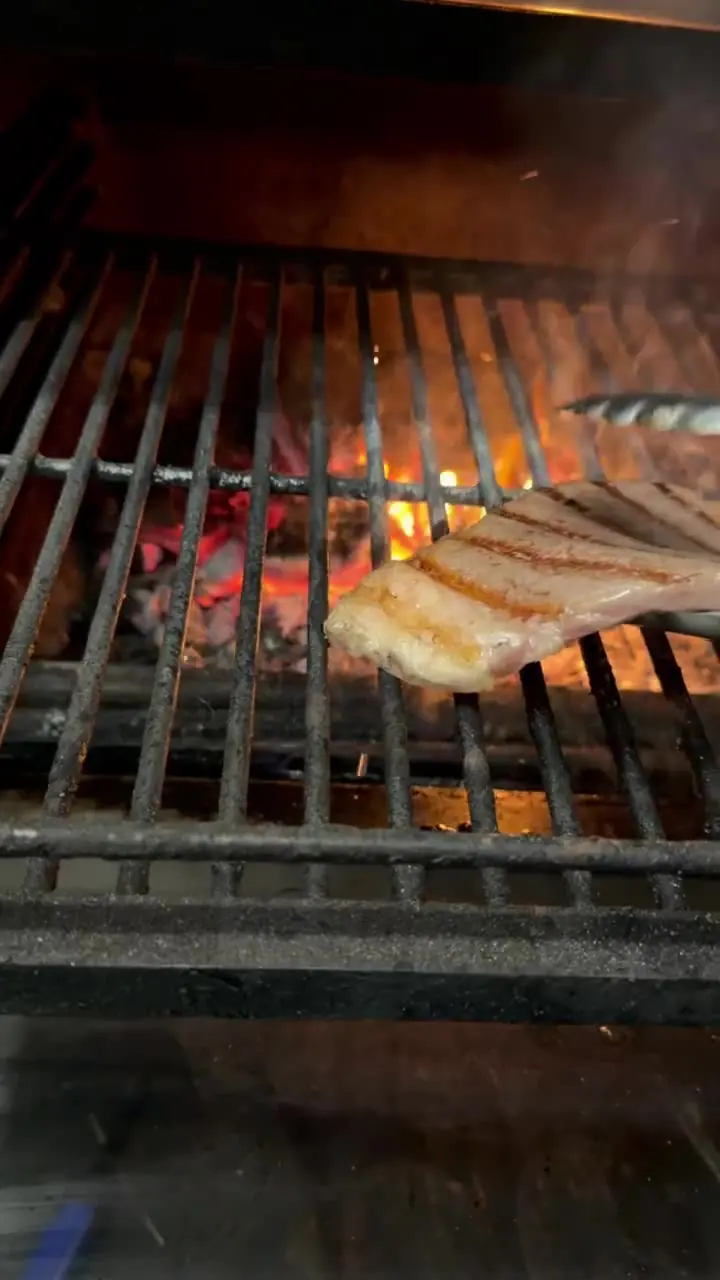 A steak searing on the bars of the grill