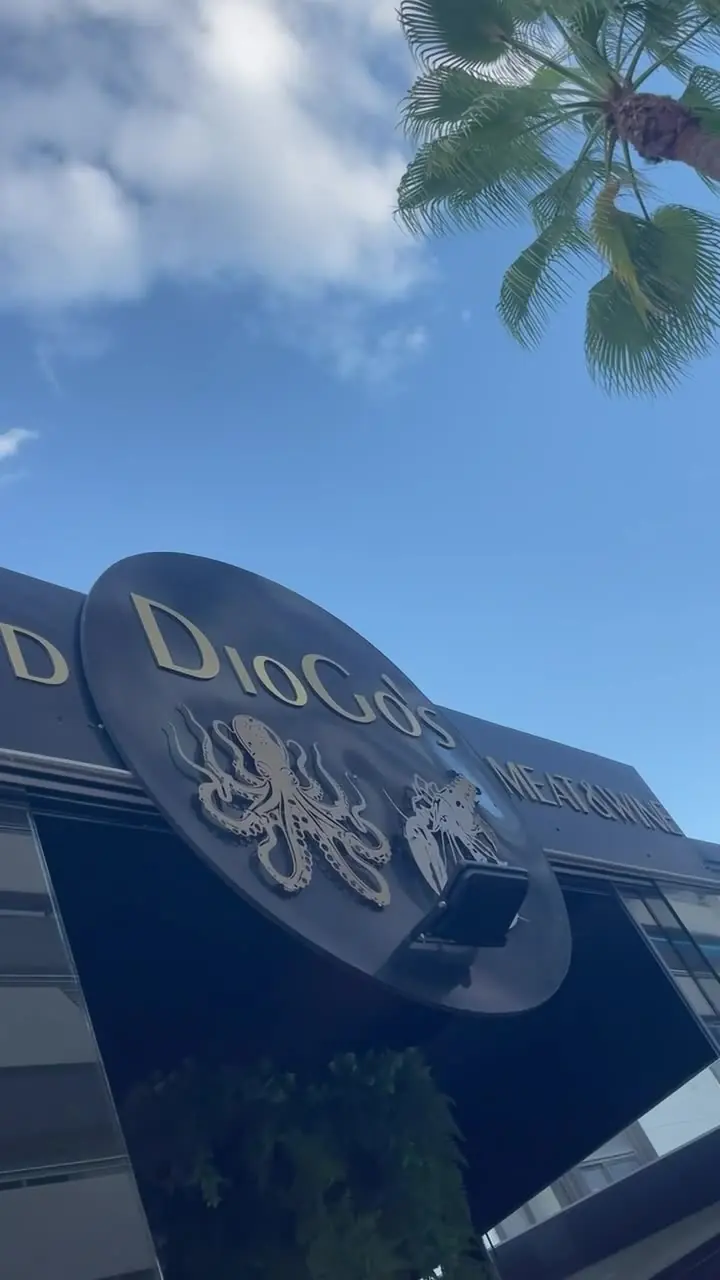 Letrero de DioGo's con un pulpo dorado bajo una palmera, restaurante de marisco en Puerto Banús